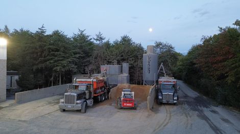 Trash truck parked outside a large industrial building at sunset