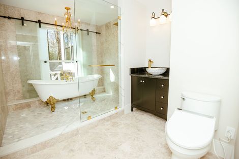 Modern bathroom with glass shower, dark vanity, white tile, and double pendant lights.