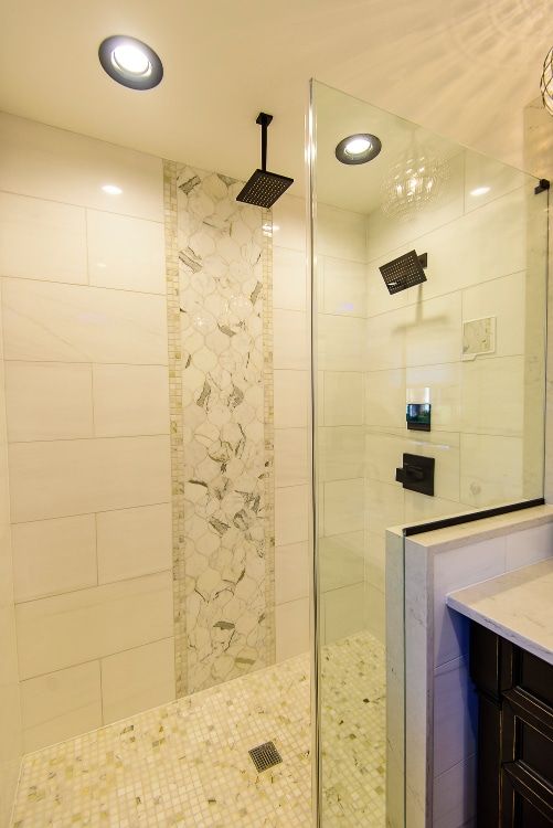Modern beige tiled shower with glass enclosure, rainfall showerhead, and mosaic floor.