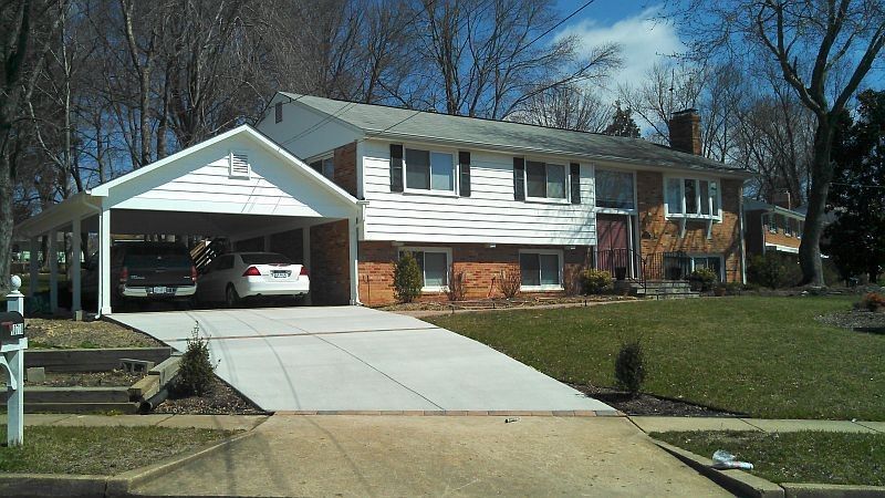 Suburban house with attached garage, white car, and a concrete driveway in front yard.