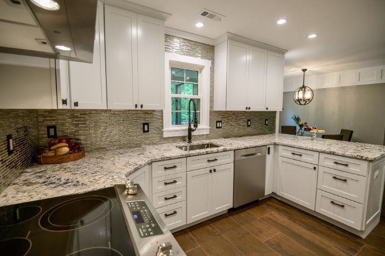 Modern white kitchen with granite counters, tiled backsplash, stainless appliances, and wood floors