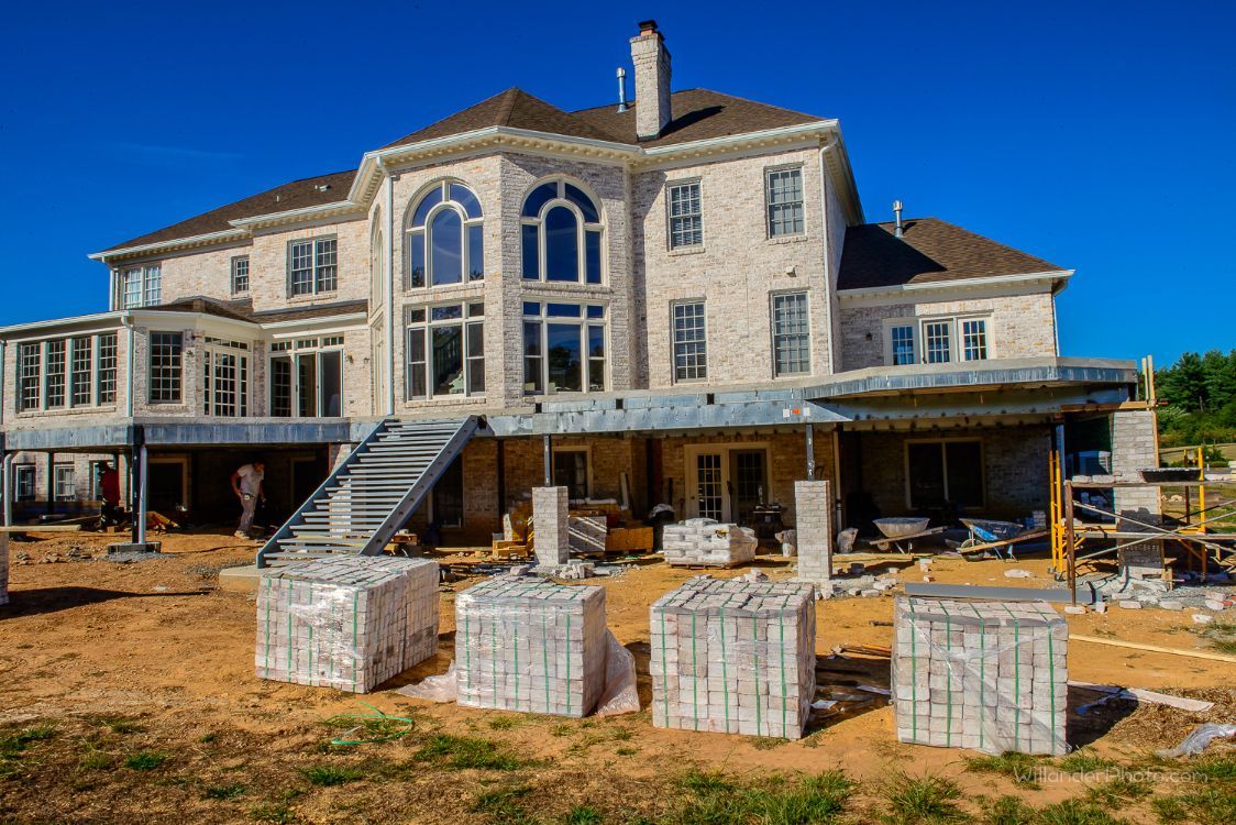 Large unfinished stone house under construction with scaffolding and building materials in front