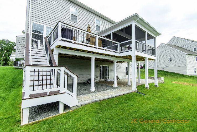 Elevated gray house with white deck and stairs over green lawn, showing an accessible raised porch.
