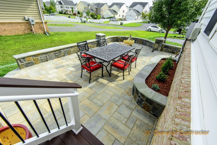 Back patio with stone pavers, black table, red chairs, and curved planter wall overlooking a neighborhood