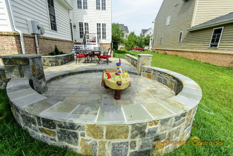 Stone backyard fire pit with built-in curved seating and a small table in the center