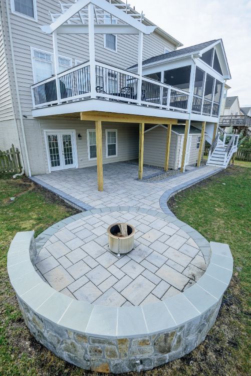 Backyard patio with circular stone fire pit and raised deck on a house