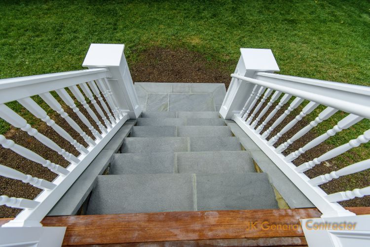 Concrete front steps with white railings leading down to a grassy yard