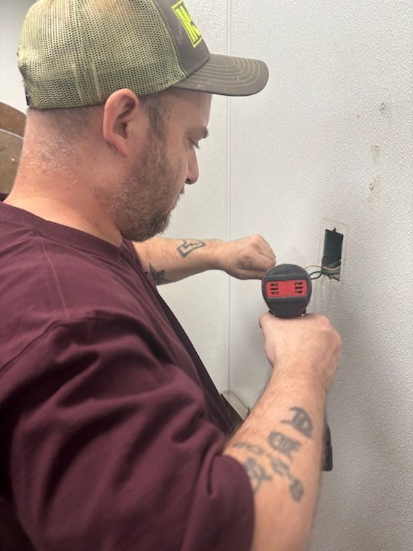 Person using a laser level to mark a wall beside an electrical box.
