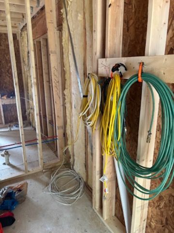Framed room under construction with coils of yellow, green, and white electrical wire on a stud wall