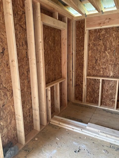 Unfinished wood-framed interior wall of a building under construction with OSB sheathing and floor joists.