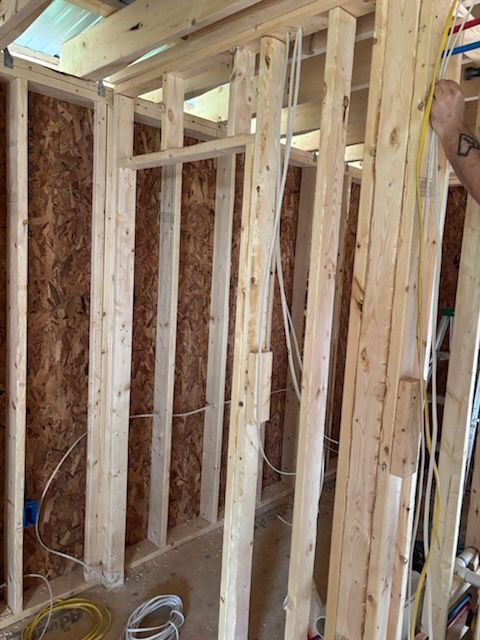 Interior of a framed room under construction with exposed wooden studs, wiring, and insulation.
