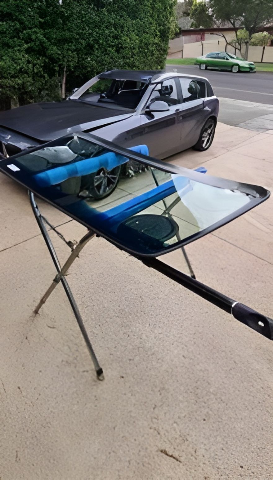 A Car is Parked in a Driveway Next to a Windscreen on a Stand — A1 CarGlass In Noosa, QLD