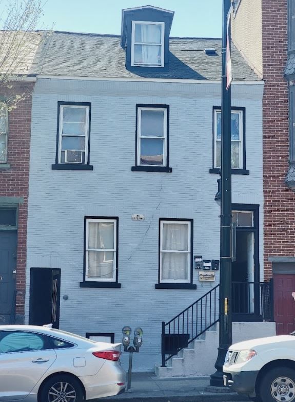 A white car is parked in front of a brick building