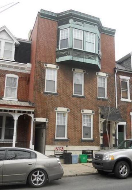 A car is parked in front of a brick building