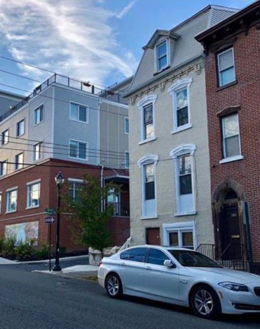 A white car is parked in front of a brick building