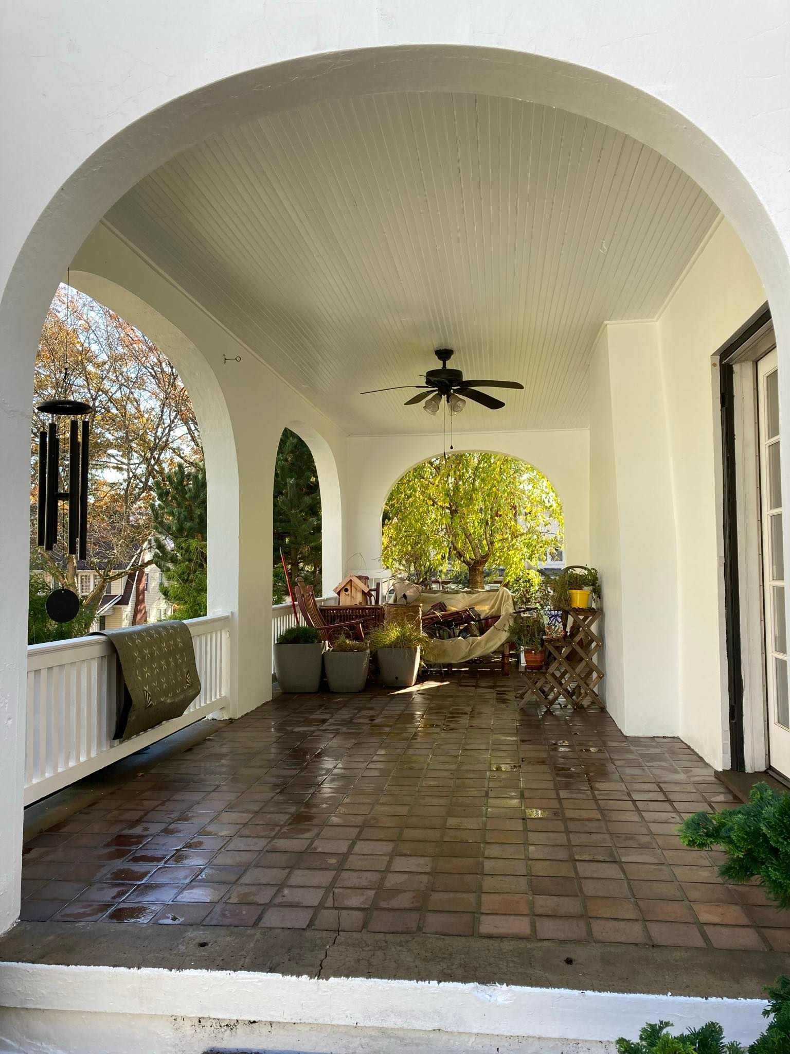 A covered, arched patio with tiled flooring, a ceiling fan, and outdoor seating visible in the background.