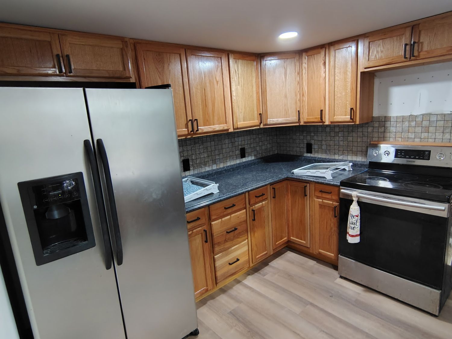 Modern kitchen with white cabinets, granite countertops, a large island, stainless steel appliances, and wood flooring.