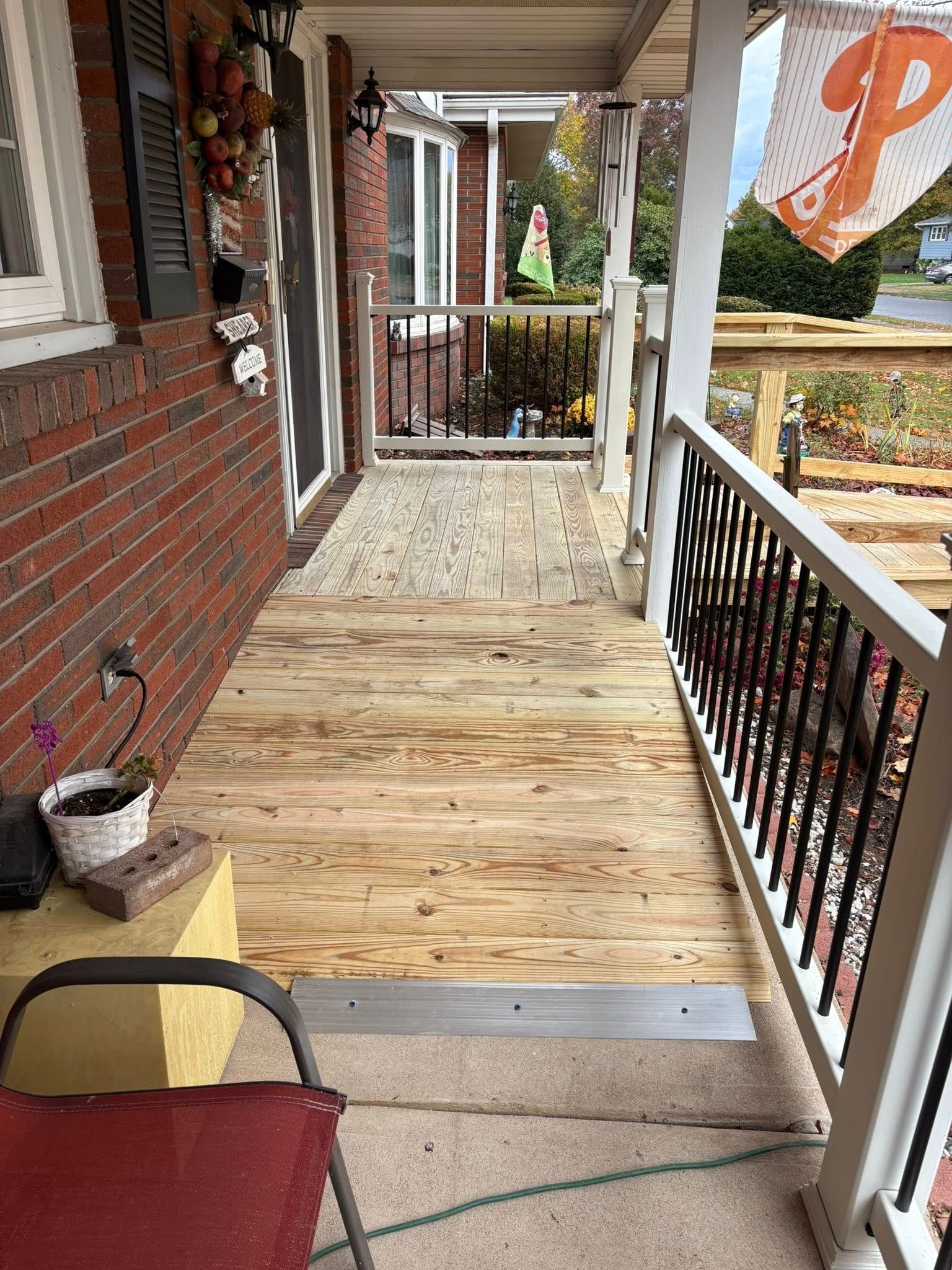 A wooden wheelchair ramp leading to a home entrance with white railings and a brick exterior.
