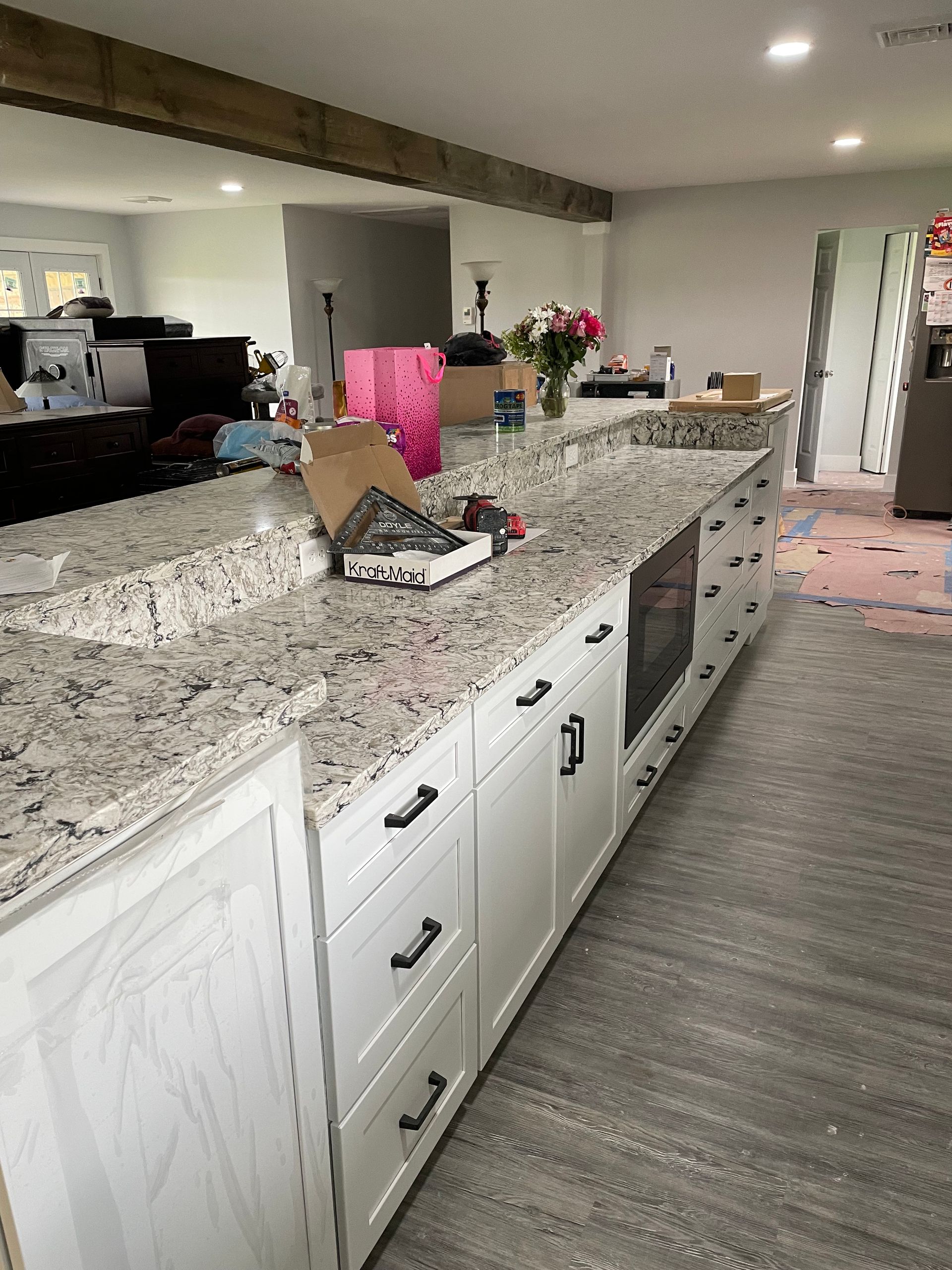 A kitchen island with white cabinets and speckled granite countertops, viewed from the side in a residential room.