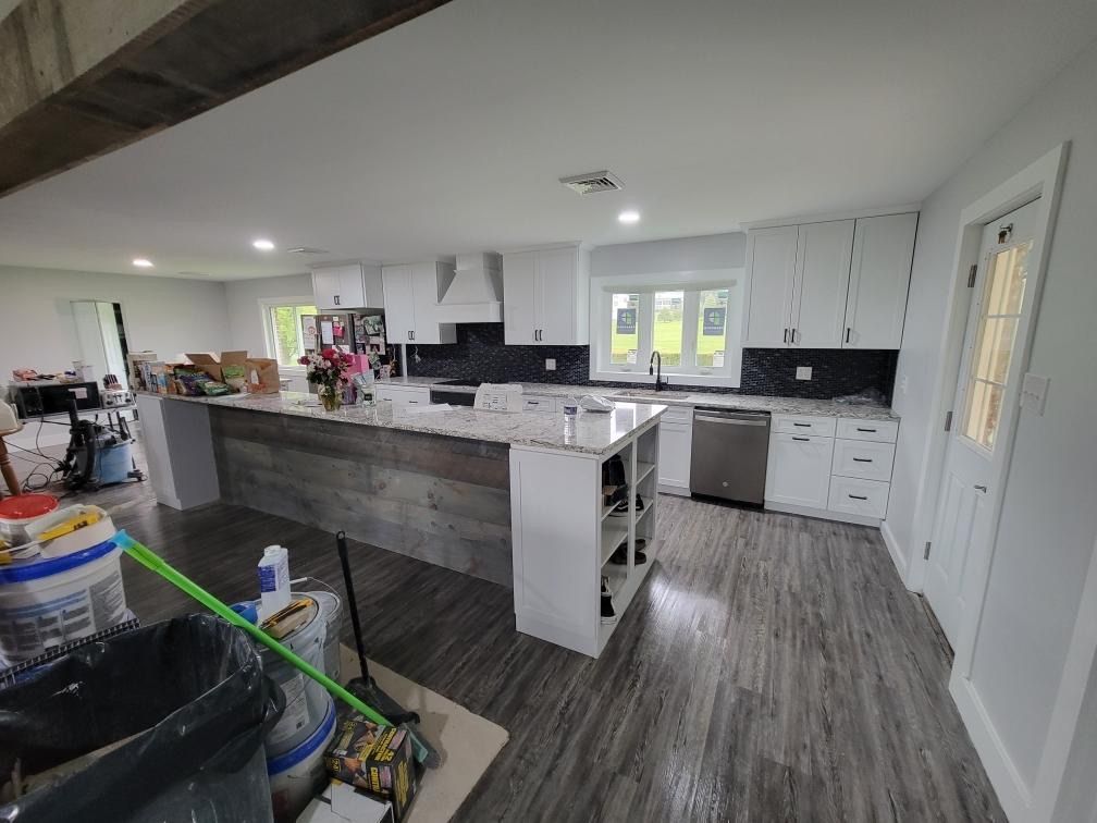 A bright, modern kitchen with white cabinets, a light-colored countertop, and a reclaimed wood-paneled kitchen island.