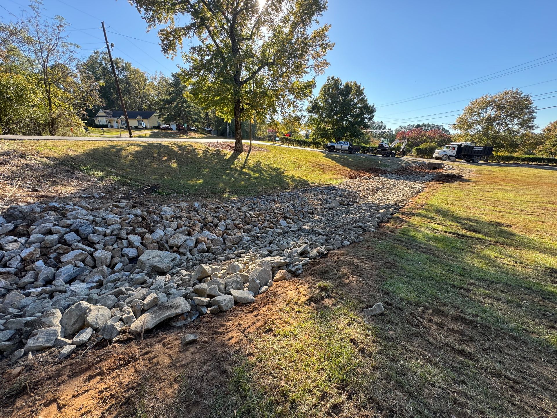 Rocky embankment with grass on either side, leading to a road under a sunny sky.