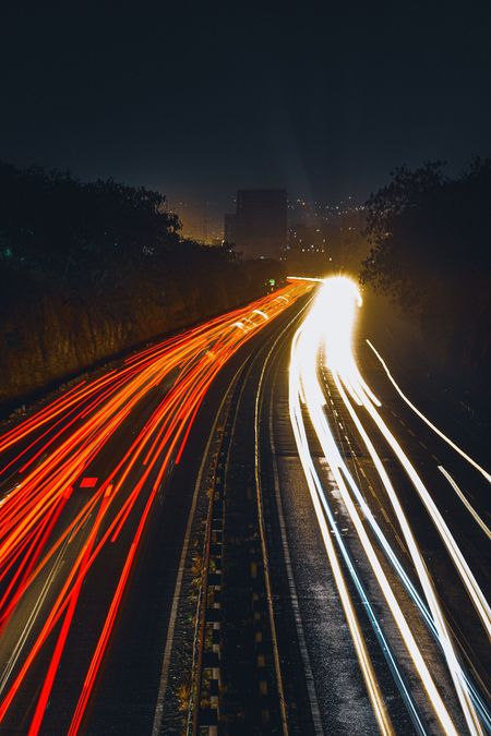 Een snelweg 's nachts met rode en witte lichtsporen van auto's die in de verte verdwijnen.
