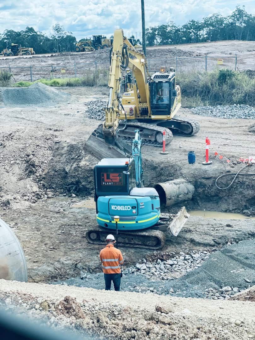 Construction Site With Two Excavators and a Worker in an Orange Vest, Digging — LS Plant Hire in Calliope, QLD
