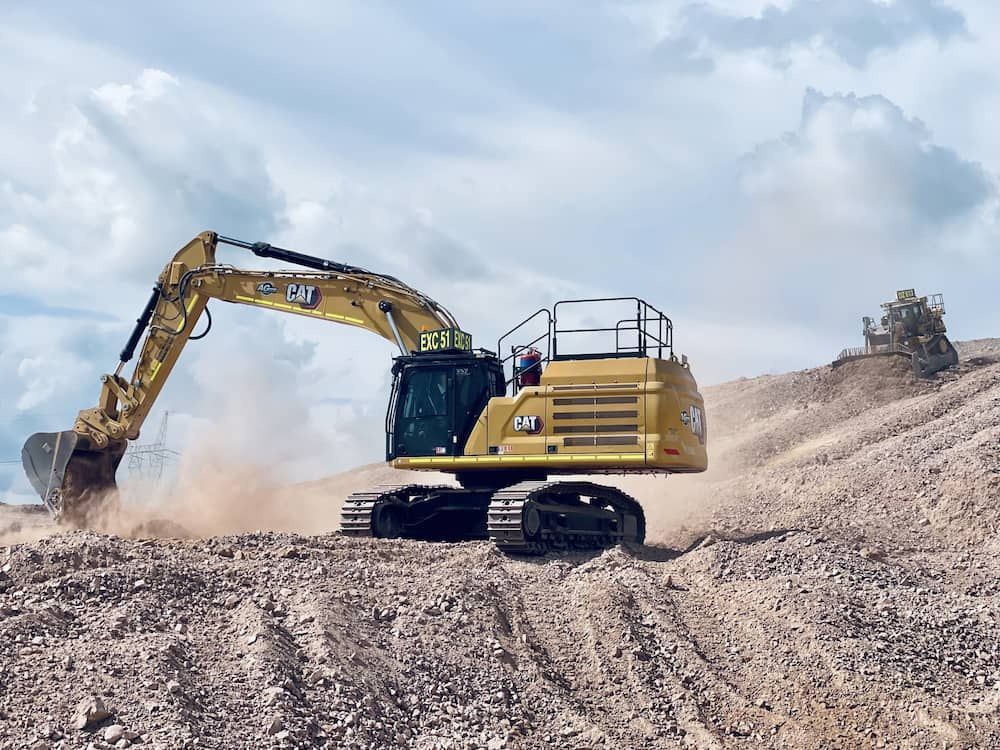 Yellow Caterpillar Excavator Digging Earth on a Hillside Under a Cloudy Sky — LS Plant Hire in Calliope, QLD