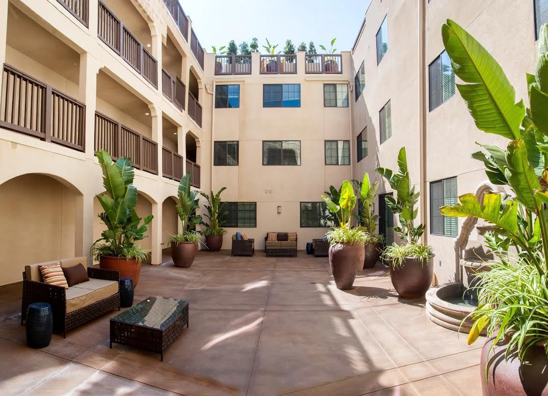 Courtyard with potted plants, seating areas, and a multi-story building.