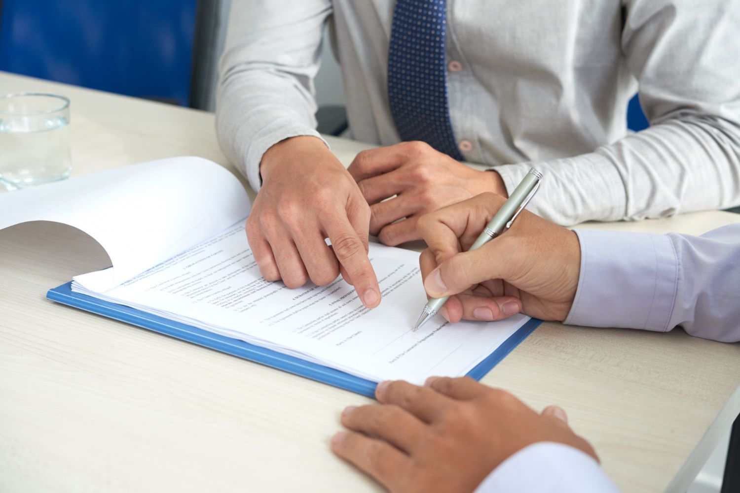 Two businesspeople in dark suits shaking hands in a bright office setting
