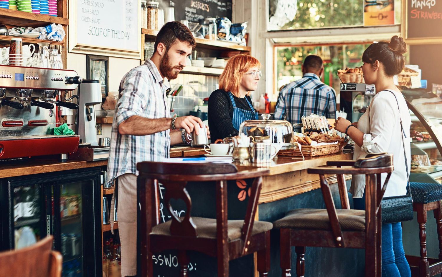 People chatting over coffee in a cozy café with a wooden table and warm decor.