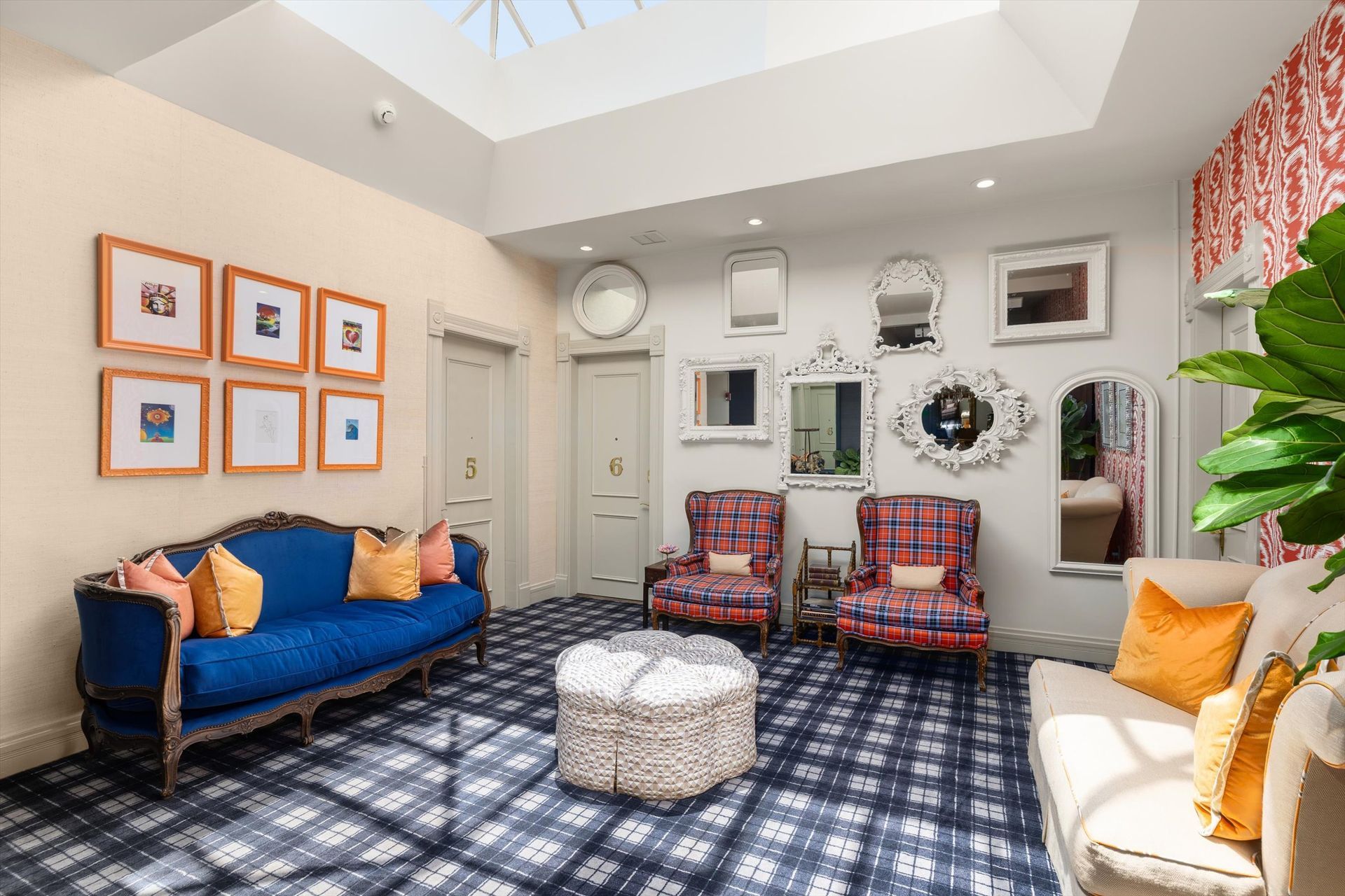 A cozy living room with a blue sofa, armchairs, mirrors, and patterned carpet.