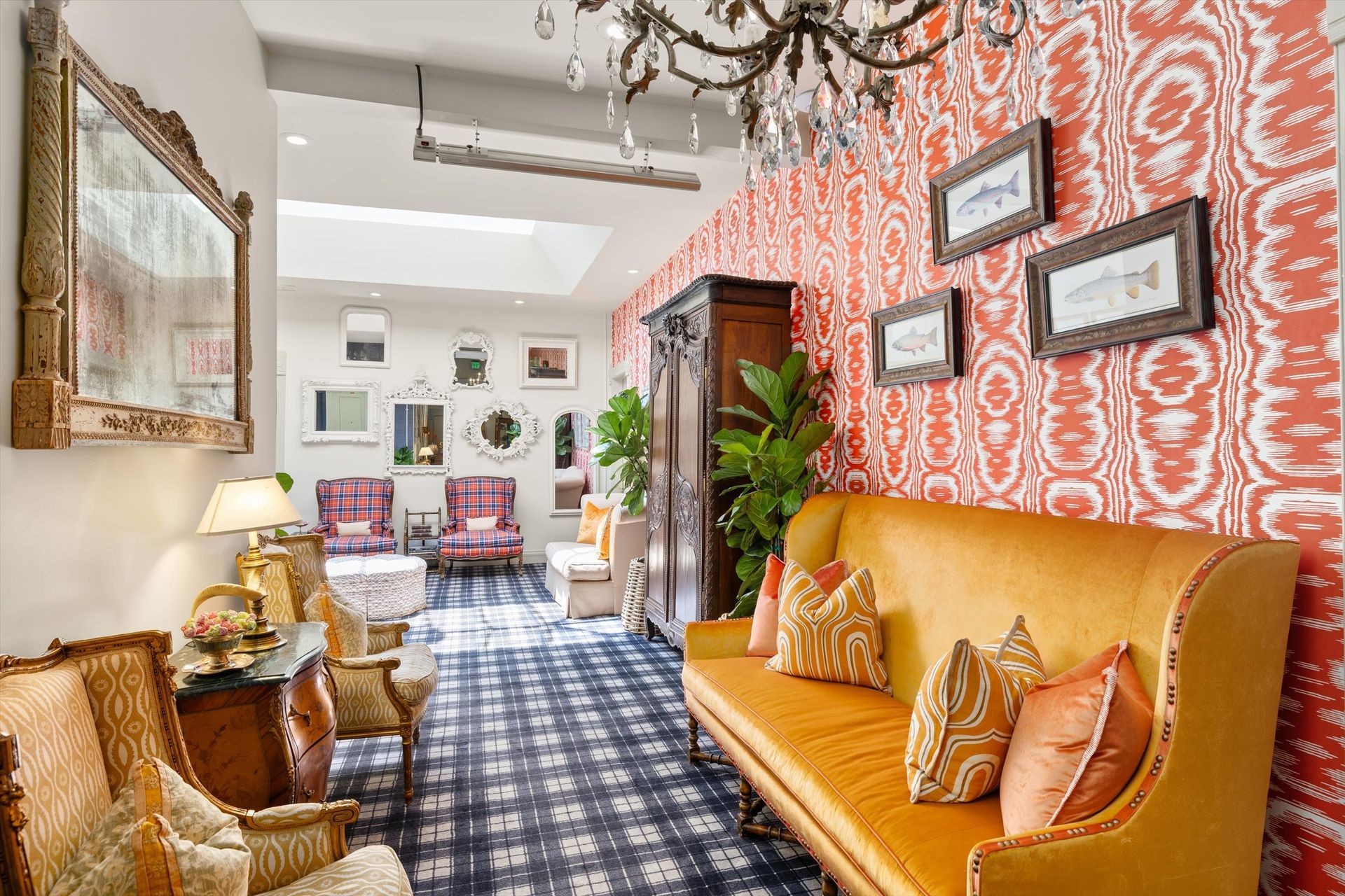Cozy hallway with patterned orange wallpaper, a gold sofa, antique furniture, and a blue and white checkered floor.