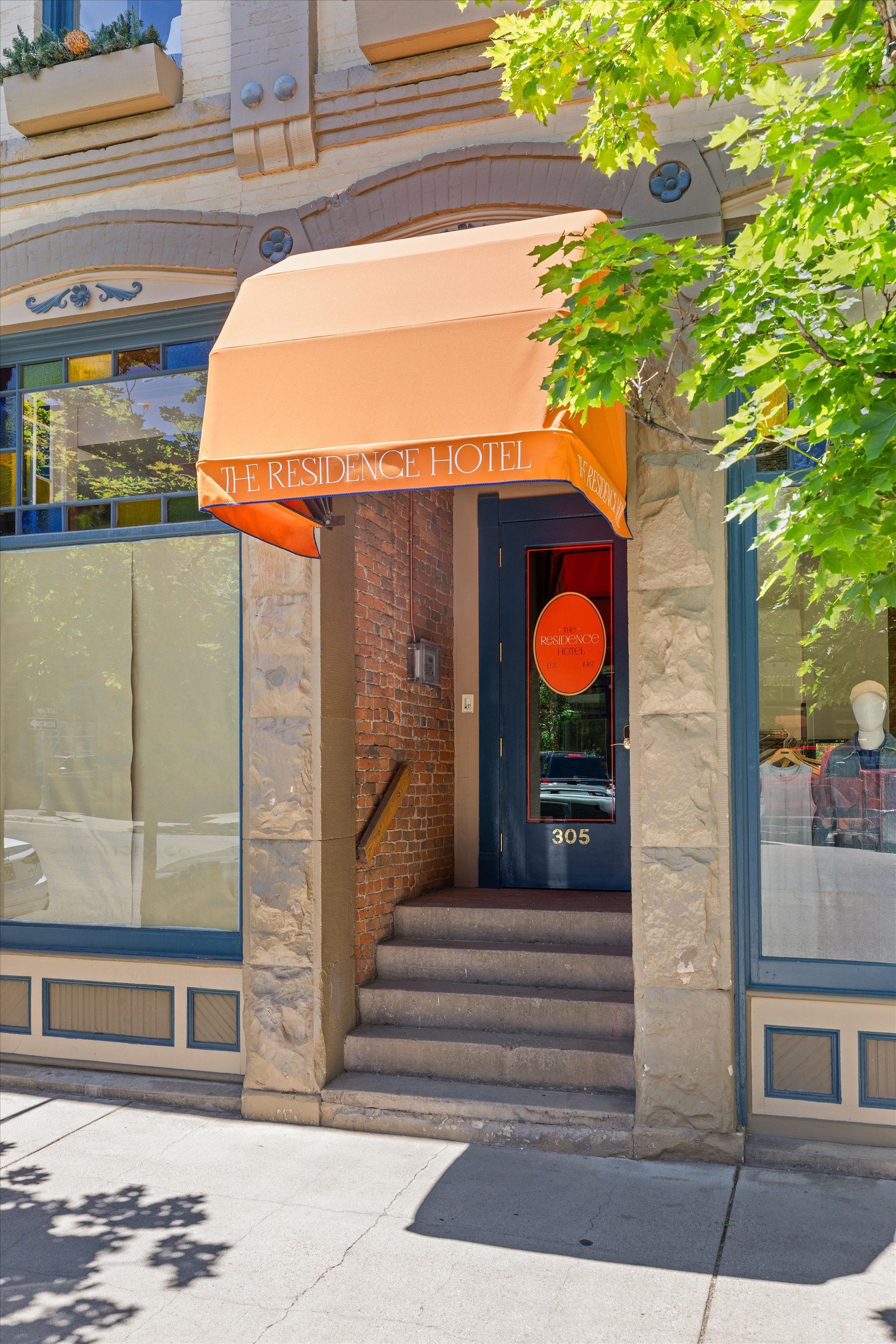 Entrance to a business with orange awning. Stone steps lead to the blue door. Sunny day.