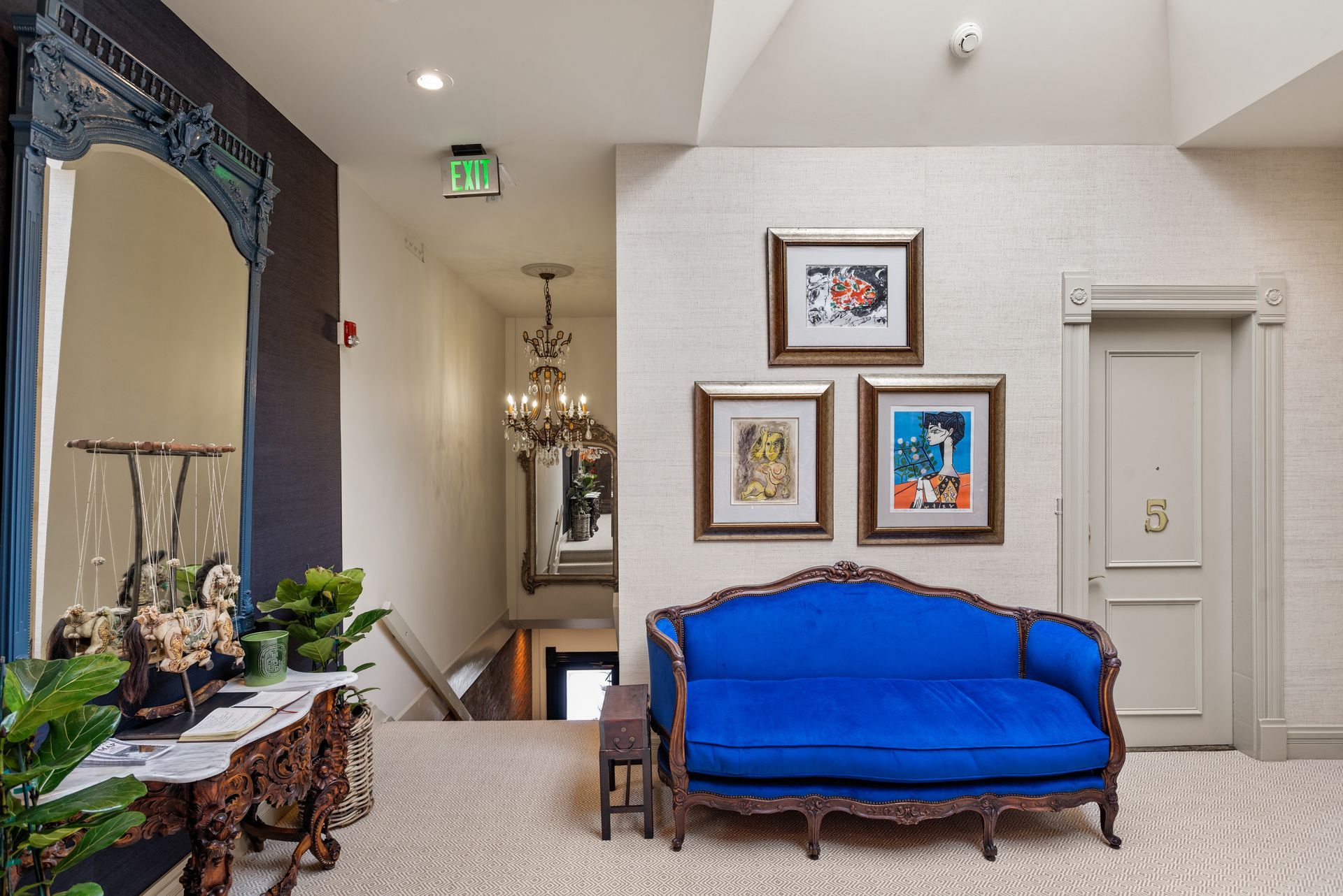 Bright blue sofa in hallway with art and a large mirror.