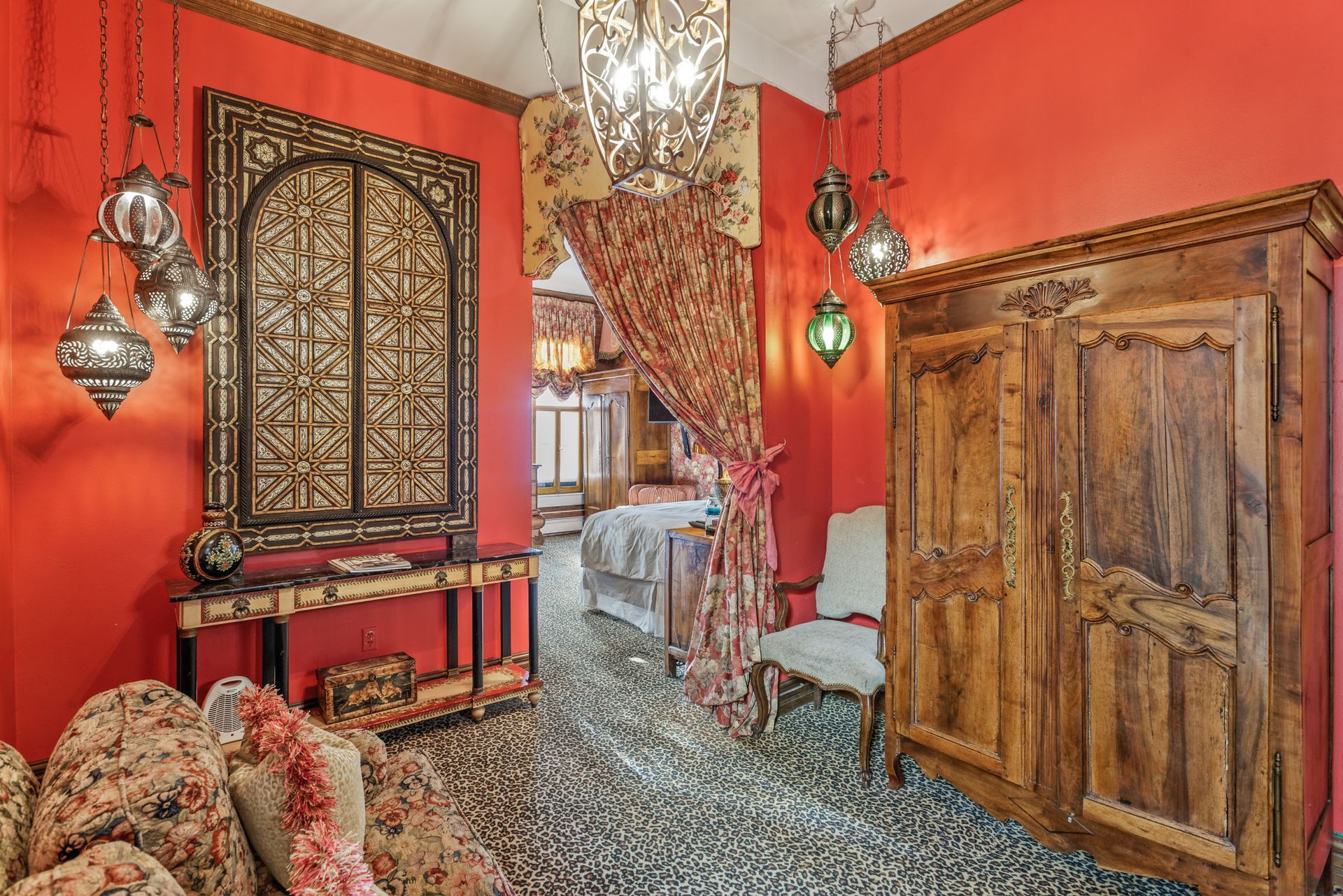 Red room with ornate decorations, including a large wooden cabinet, carved archway, and patterned floor.