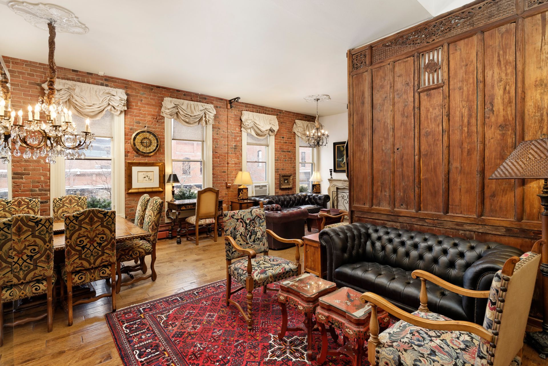 Living room with exposed brick walls, antique furniture, and a large rug.