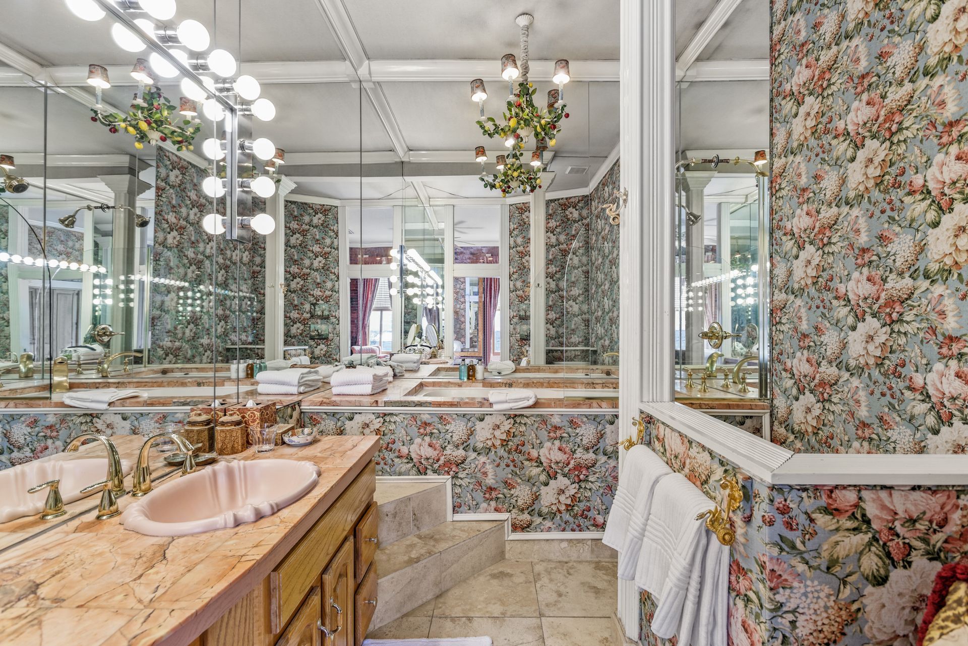 Floral wallpapered bathroom with mirrors, sinks, and decorative lighting.