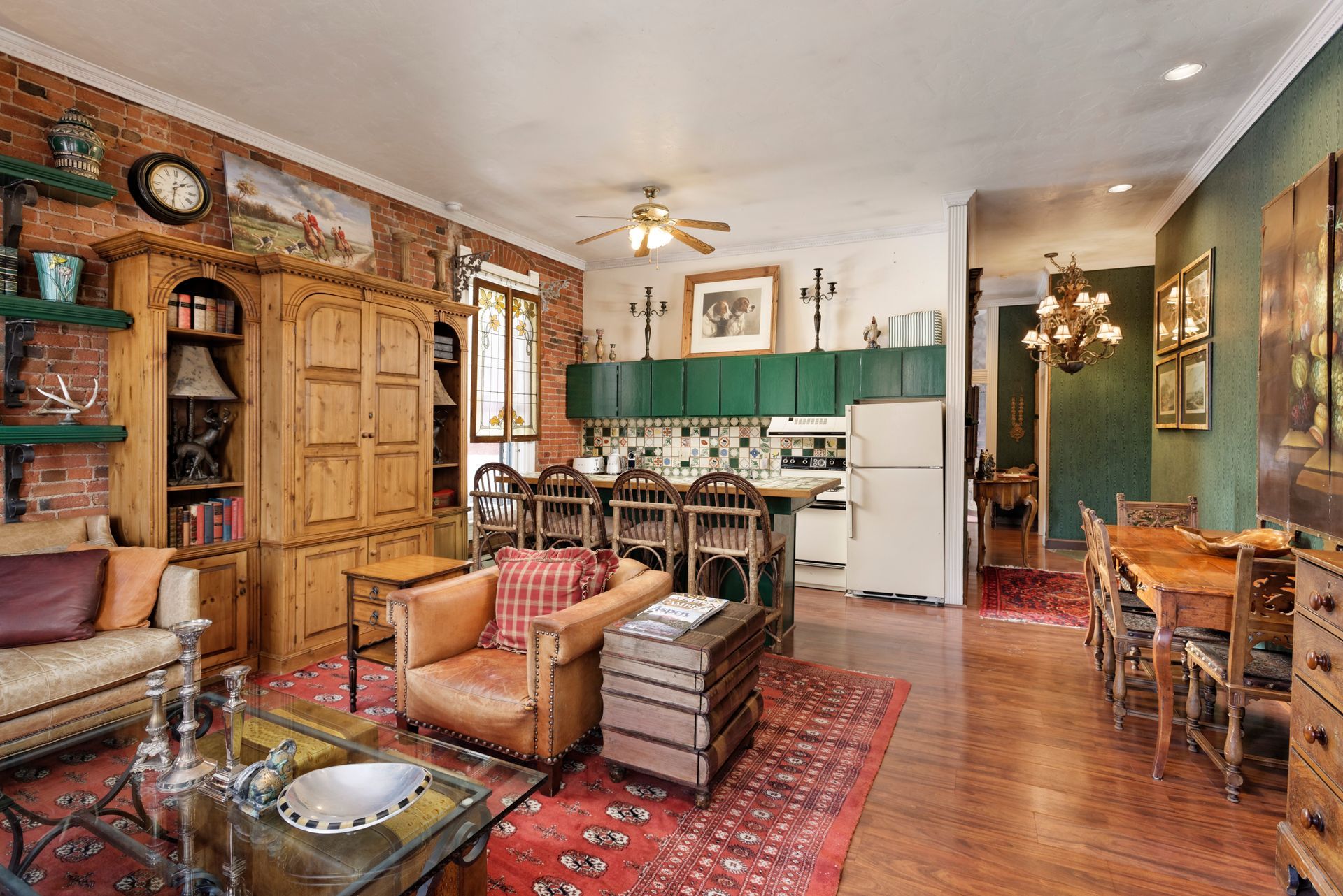 Living room with exposed brick wall, wood furniture, and kitchen area.