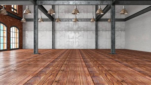 Empty industrial loft with wooden floors, exposed brick, and large windows.