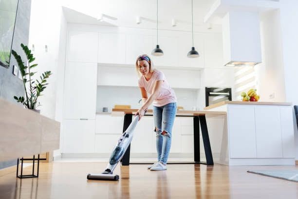 Person mopping a bright modern kitchen floor with a spray mop.