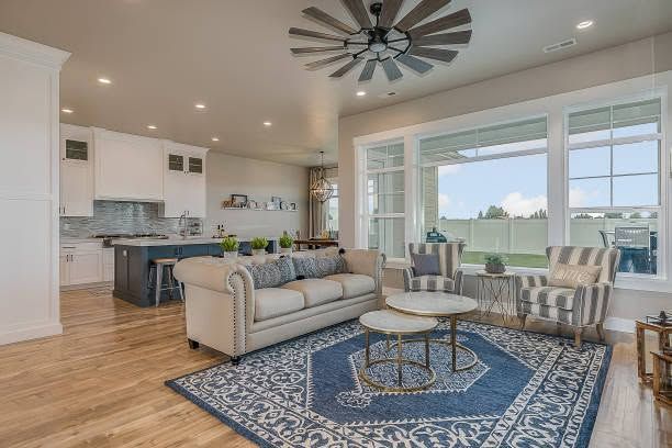 Bright open living room with beige sofa, blue rug, and kitchen island in background