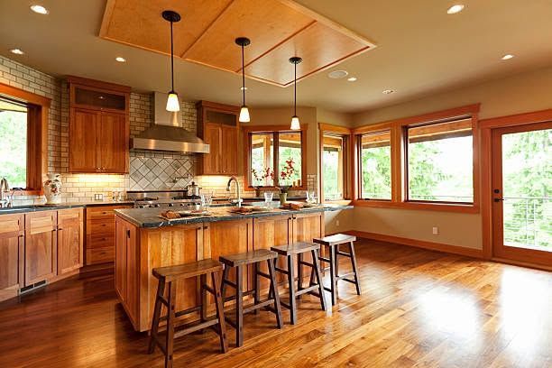 Spacious modern kitchen with wooden cabinets, island seating, and large windows overlooking a bright room