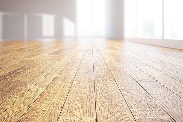 Empty sunlit room with light wood floor and large bright windows