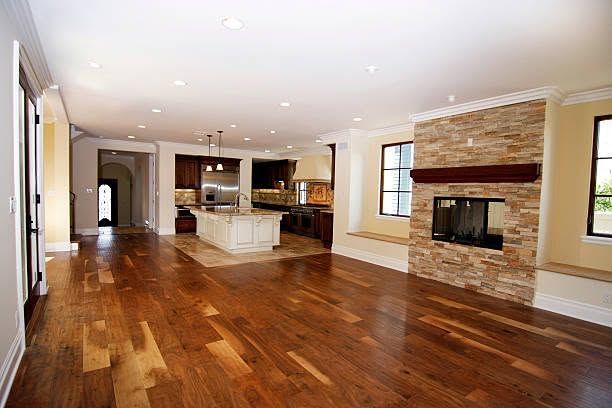 Spacious open-plan living room with hardwood floors, kitchen island, and brick fireplace