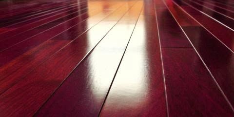 Glossy red wooden floorboards with bright reflected light