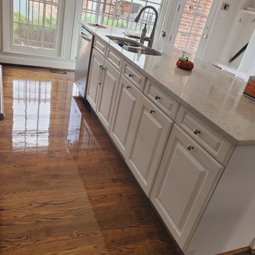 Bright kitchen with white island cabinets, marble countertop, sink, and sunlit hardwood floor.