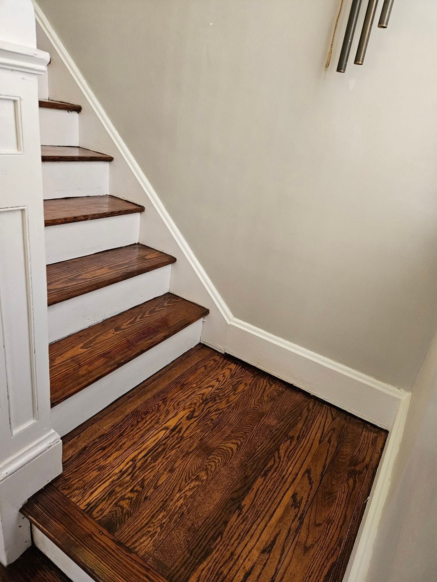 Wooden staircase with white trim and a matching hardwood landing in a home interior