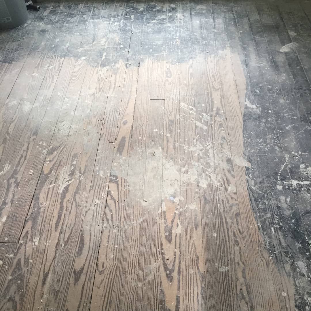 Worn wooden floorboards with a large faded patch and dark edges under soft light