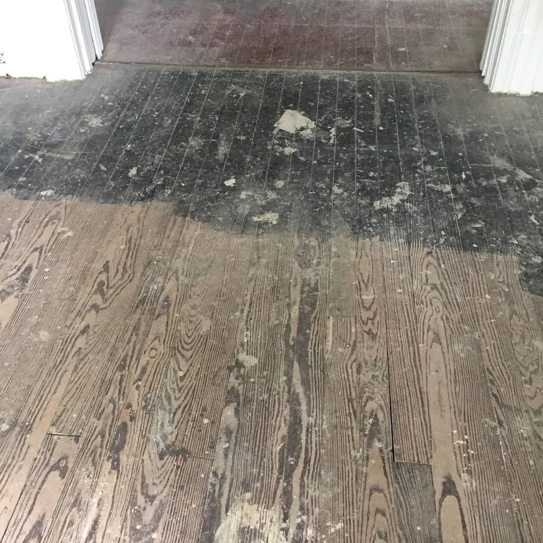 Damaged wooden floor with a dark stripped section near a hallway entrance